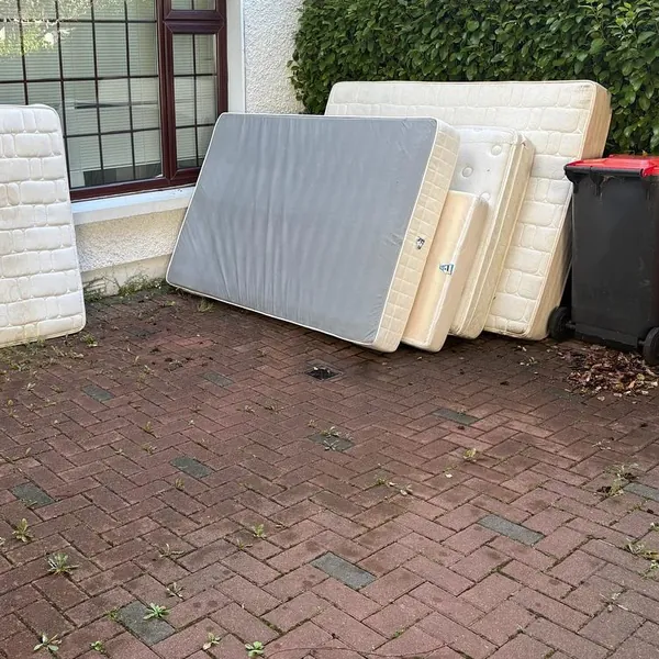 Mattresses and bed bases leaning against a house, waiting to go