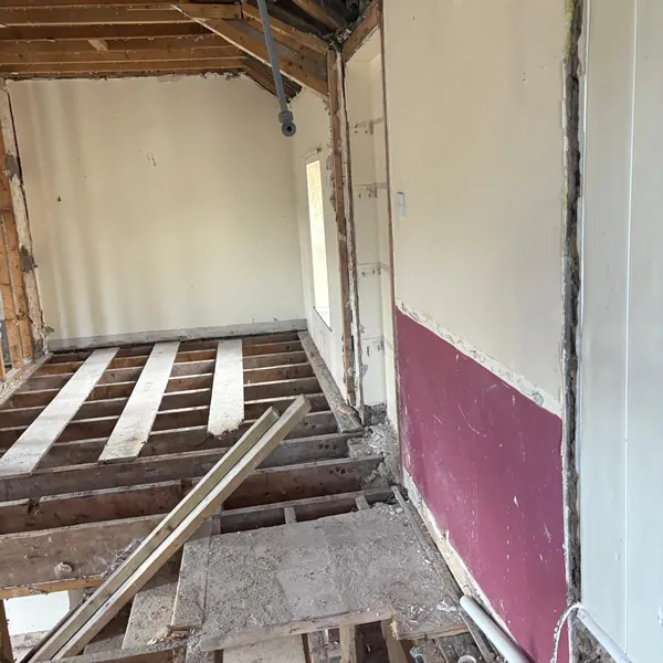 Floorboards up and the ceiling open in a stripped room
